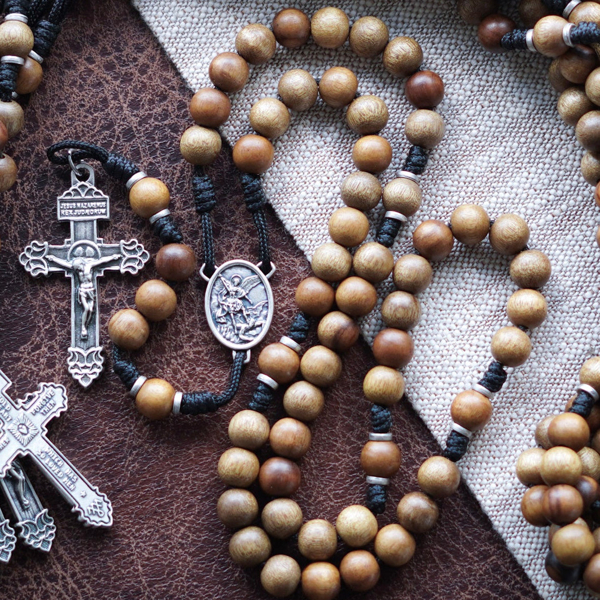 Wooden rosary beads with St. Michael medal on a textured fabric background